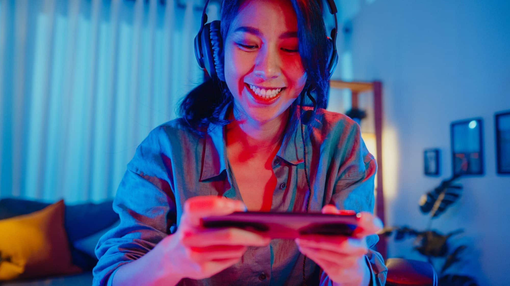 asia girl gamer wear headphone competition play video game online with smartphone.