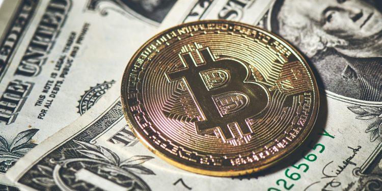Bitcoin coin resting to paper dollars