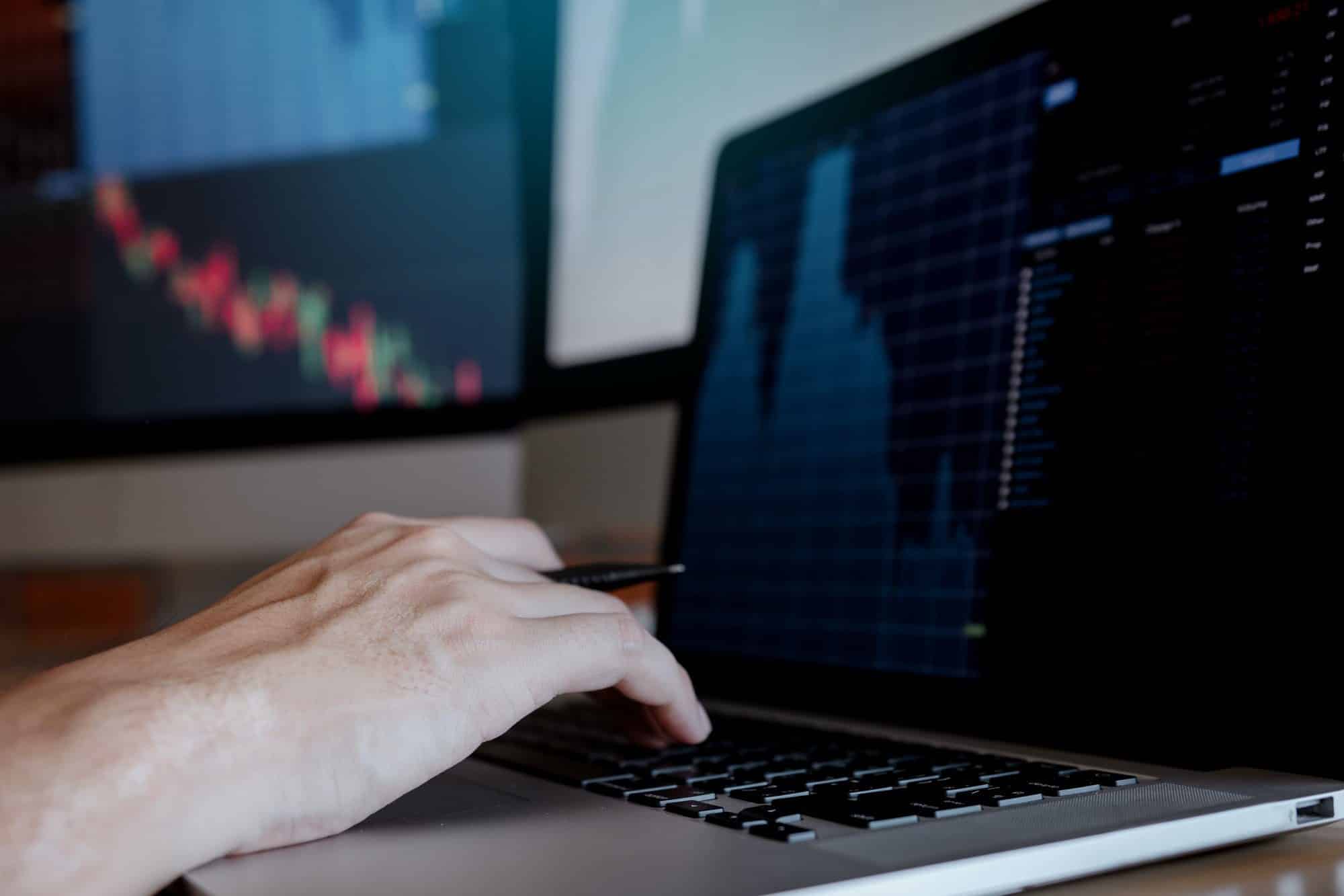 Businessman typing on keyboard laptop and working trading stock market in office room.