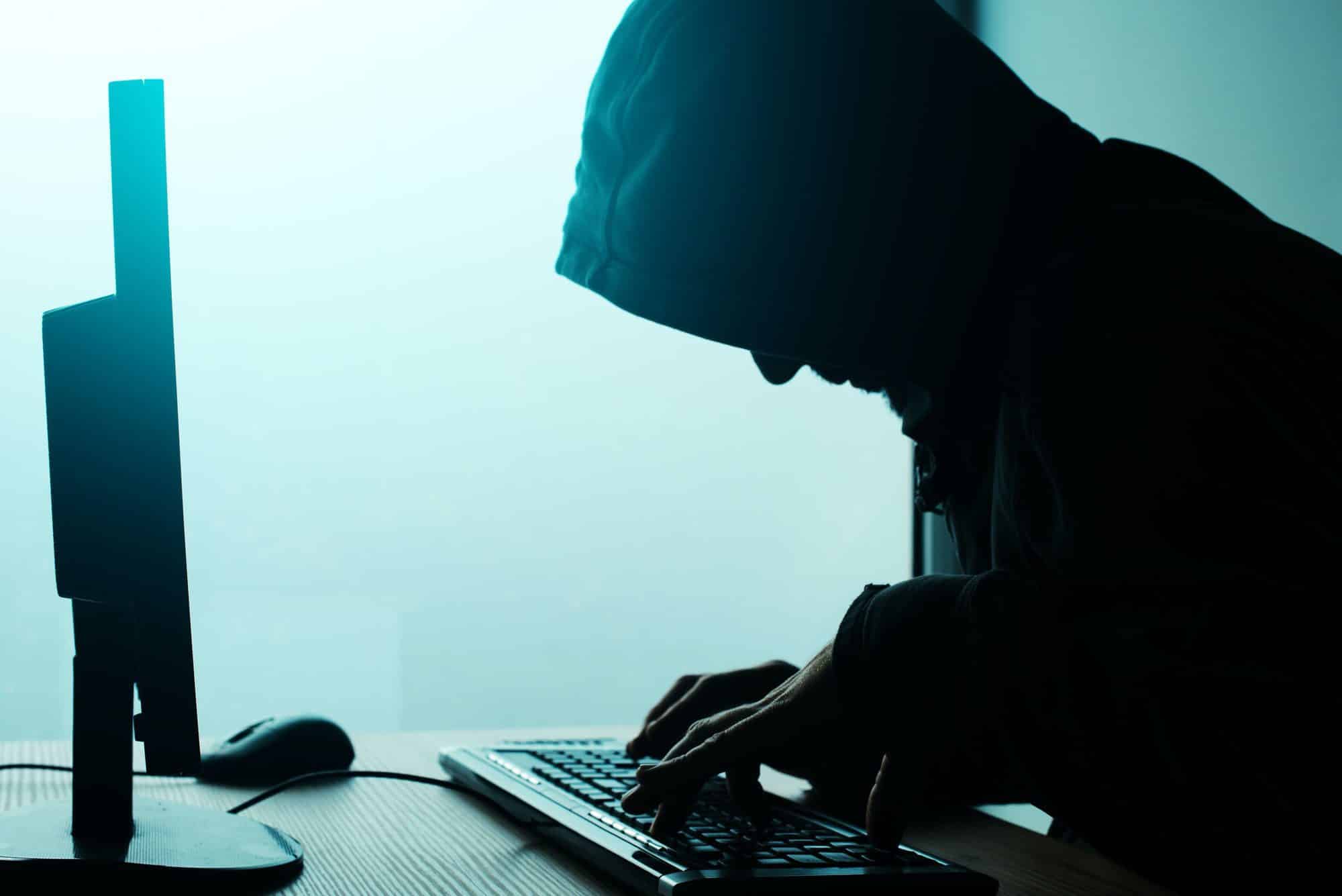 Hooded computer hacker hacking network