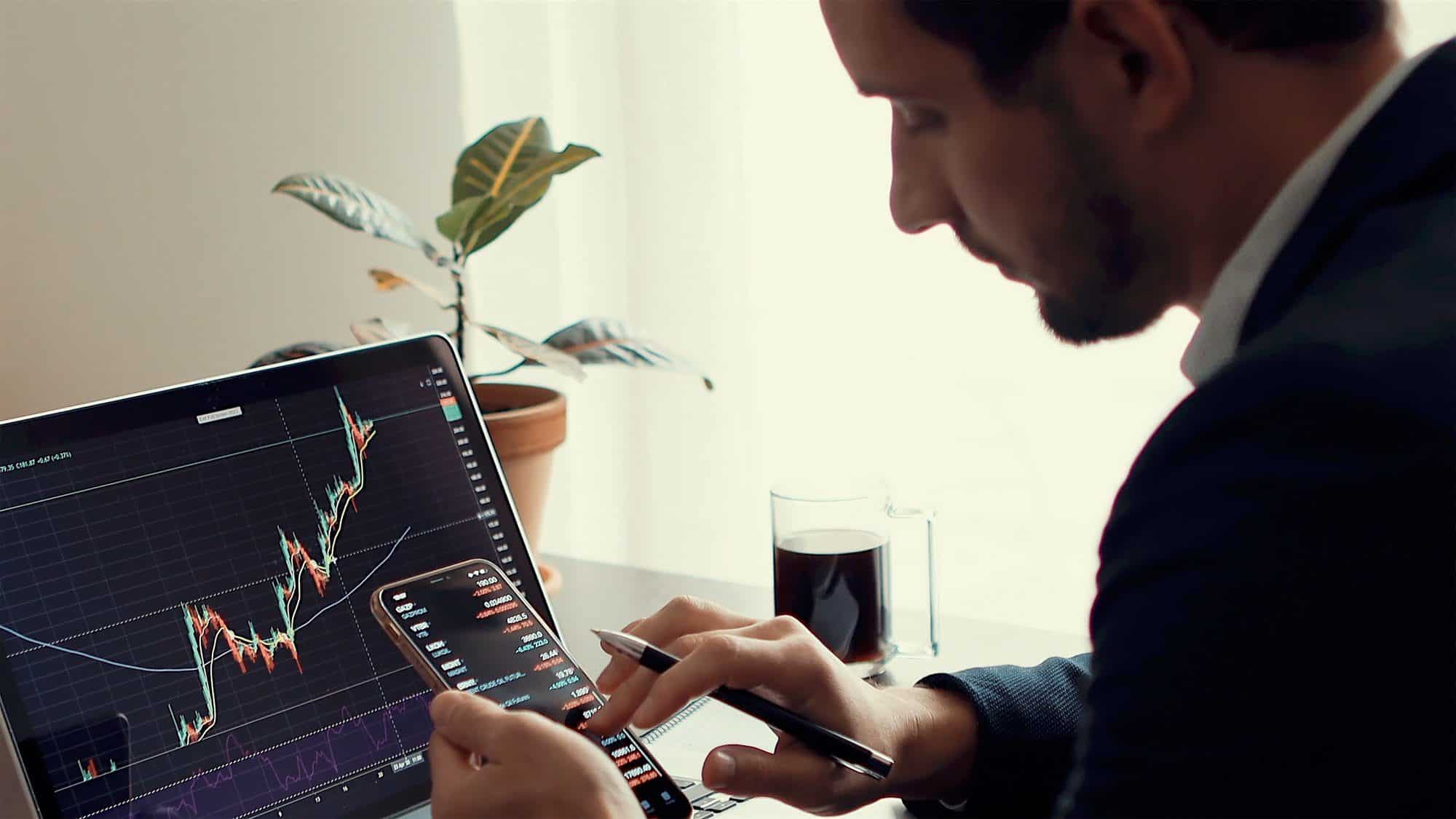 Investment broker trading bitcoin crypto currency using phone and laptop