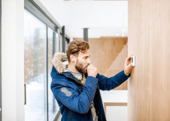 Man adjusting temperature with thermostat at home