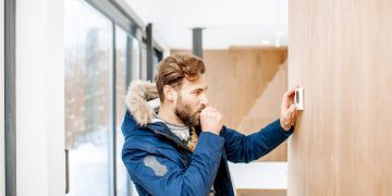 Man adjusting temperature with thermostat at home