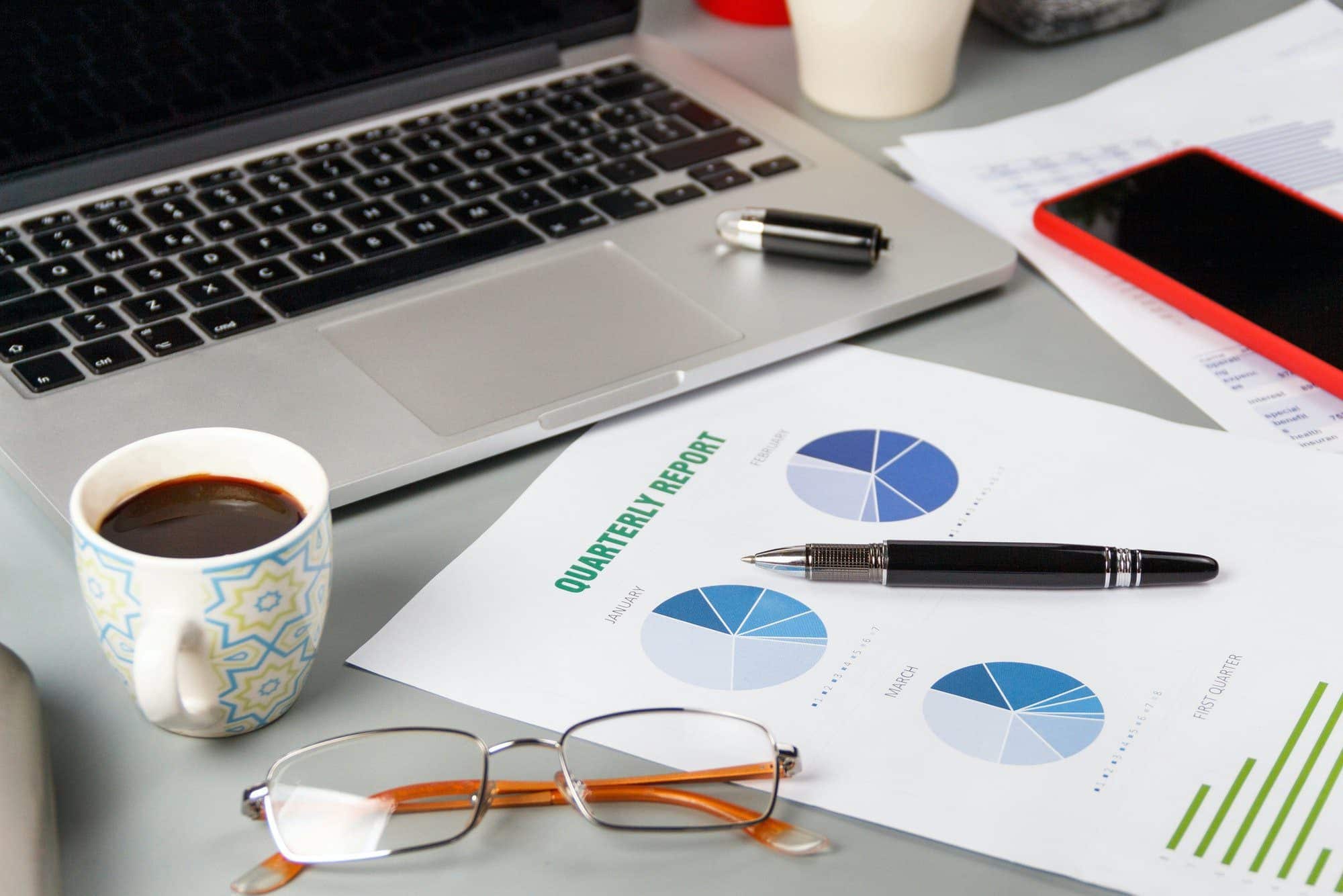 Modern office grey desk with reports and modern gadgets close up
