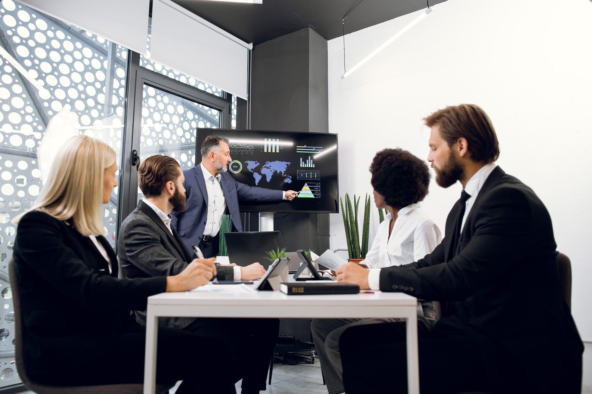 Multiethnic financial experts investors, sitting at the table in office, while handsome middle aged