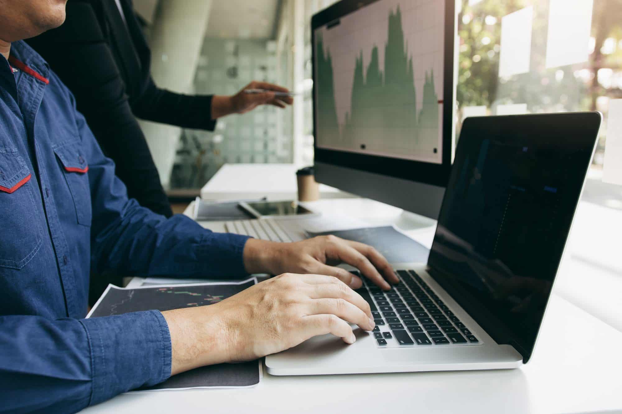 Two investors work together and note the stock price to compare with other stocks.